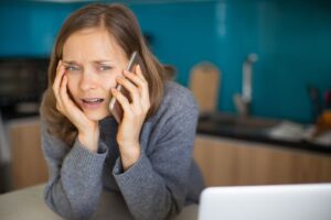 young woman on phone with confused look on face