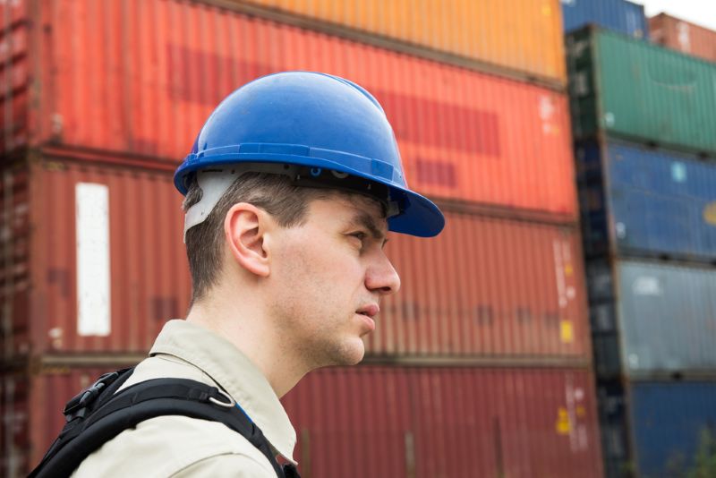 dock worker standing in front of cargo containers