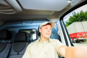 smiling young man driving a company vehicle at work