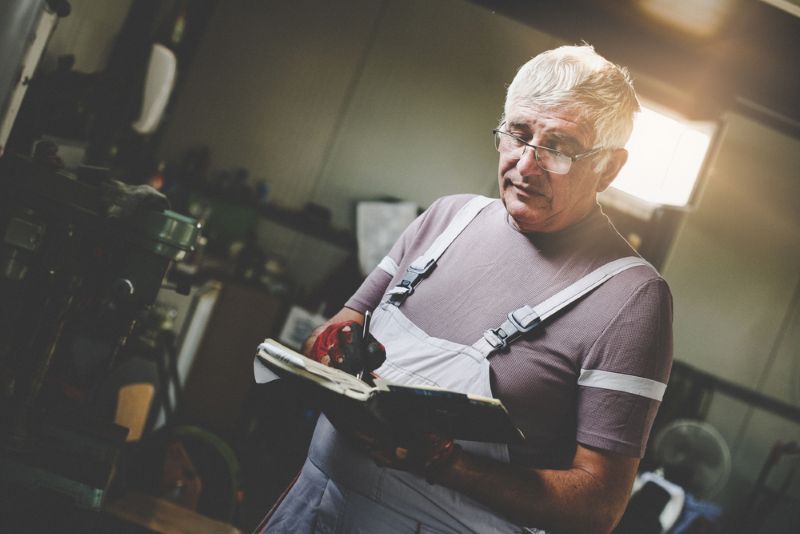 Older man taking notes while working in his workshop