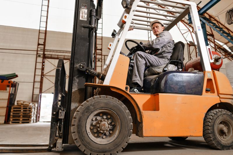 Forklift operator driving through warehouse