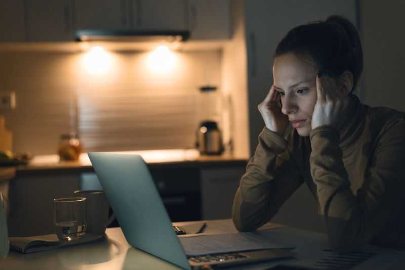 Stressed woman working on her laptop in kitchen